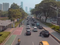Mobil dan sepeda motor melaju di jalan raya Jakarta berlatar gedung tinggi