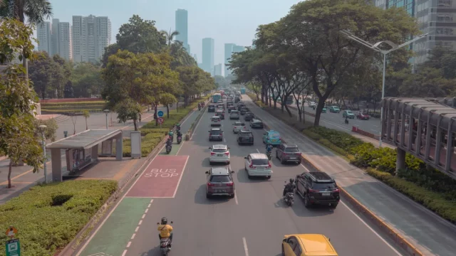 Mobil dan sepeda motor melaju di jalan raya Jakarta berlatar gedung tinggi