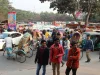 Kerumunan pejalan kaki, becak, dan mobil memadati jalan Kota Dhaka, Bangladesh, pada siang hari