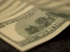 Lembaran uang seratus dolar Amerika Serikat tersusun bertumpuk di permukaan gelap