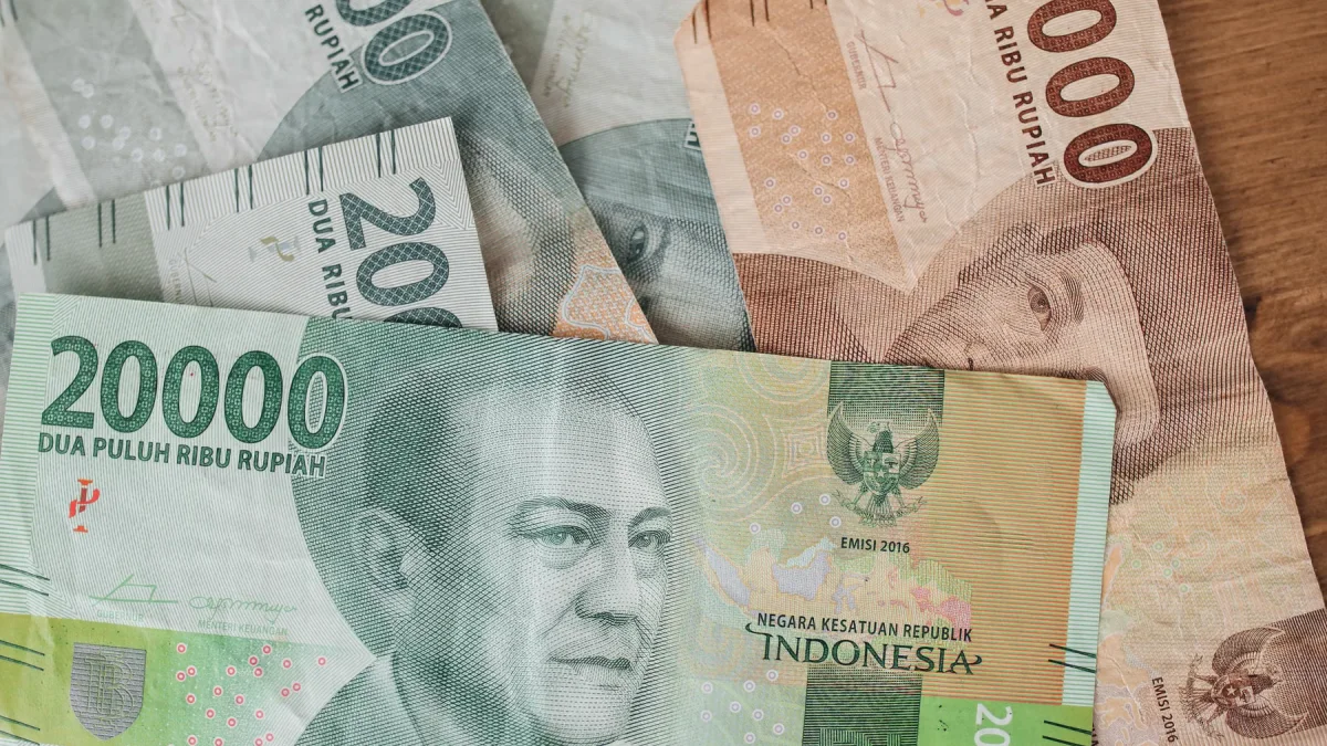 Lembaran uang kertas rupiah berbagai pecahan tergeletak di atas meja kayu