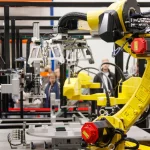 Lengan robot kuning bekerja di fasilitas produksi