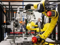 Lengan robot kuning bekerja di fasilitas produksi