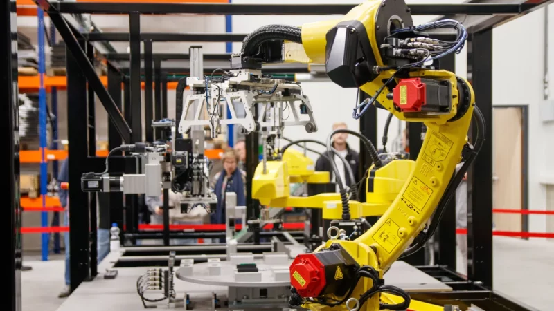 Lengan robot kuning bekerja di fasilitas produksi