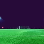 Pemain sepak bola menggiring bola di lapangan