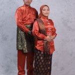 Ilustrasi sepasang orang mengenakan busana songket merah lengkap dengan penutup kepala.