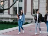 Tiga mahasiswa berjalan bersama di trotoar kampus