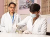 Dua mahasiswa berjas lab putih melakukan praktikum di laboratorium kampus di India