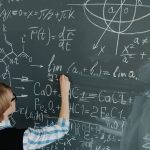 Ilustrasi seorang perempuan menuliskan deretan rumus matematika dengan kapur pada papan tulis hijau yang penuh coretan.