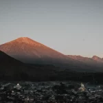 Gunung Rinjani diterpa cahaya matahari terbit di atas permukiman di Nusa Tenggara Barat