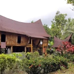 Rumah Lontiok beratap melengkung berdinding kayu di tengah taman, Kabupaten Kampar, Riau