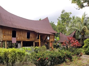 Rumah Lontiok beratap melengkung berdinding kayu di tengah taman, Kabupaten Kampar, Riau