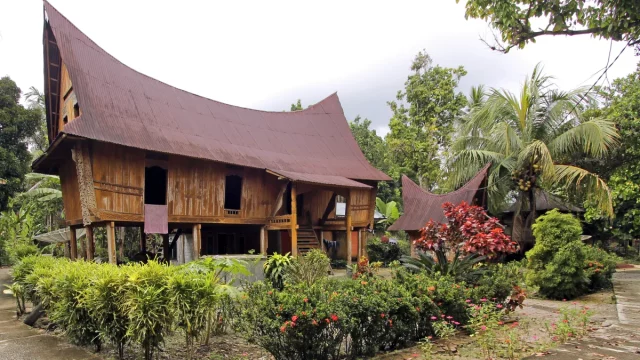 Rumah Lontiok beratap melengkung berdinding kayu di tengah taman, Kabupaten Kampar, Riau