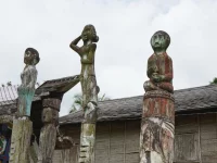Tiga patung sapundu kayu berdiri di depan rumah Betang Toyoi, Kalimantan