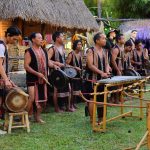 Ilustrasi kelompok musik tradisional menabuh gendang dan gong di panggung terbuka.