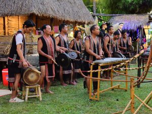 Ilustrasi kelompok musik tradisional menabuh gendang dan gong di panggung terbuka.