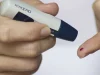 Tangan menusuk ujung jari dengan alat lancet untuk memeriksa gula darah