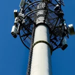 Ilustrasi menara telekomunikasi dengan antena di bawah langit biru