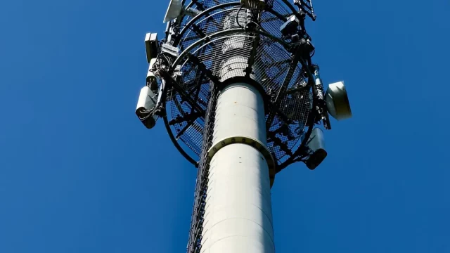Ilustrasi menara telekomunikasi dengan antena di bawah langit biru