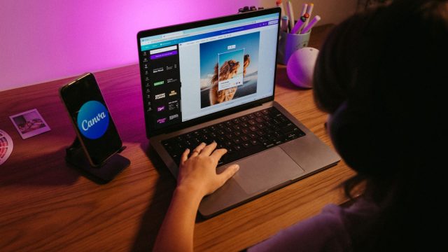 Ilustrasi seorang remaja mengerjakan desain di laptop dengan pencahayaan berwarna.