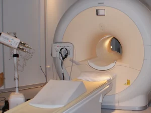 Mesin pemindai MRI dengan meja pasien di ruang pemeriksaan rumah sakit