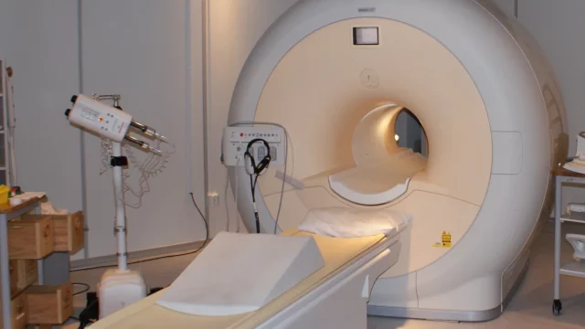Mesin pemindai MRI dengan meja pasien di ruang pemeriksaan rumah sakit