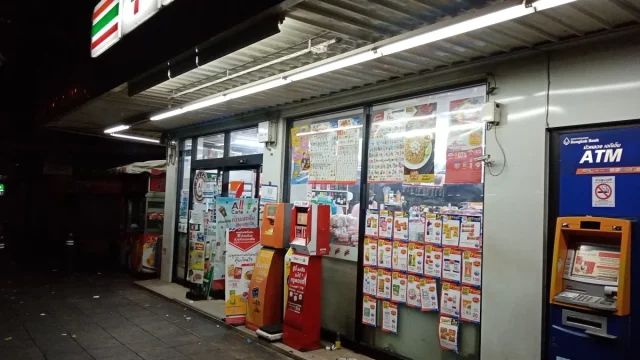 Fasad gerai 7-Eleven dengan mesin ATM pada malam hari di Bang Yi Ruea, Bangkok, Thailand