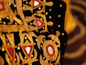 Sulaman benang emas berhias kaca cermin dan kain merah pada dasar beludru hitam