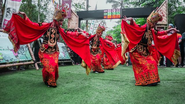 Penari Gandrung Banyuwangi berkostum merah menari di panggung terbuka.
