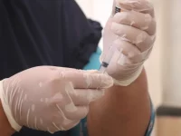 Tangan petugas kesehatan bersarung tangan lateks menyiapkan jarum suntik vaksin dari botol kecil