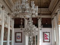 Ilustrasi aula istana bergaya lama dengan deretan lampu gantung kristal.