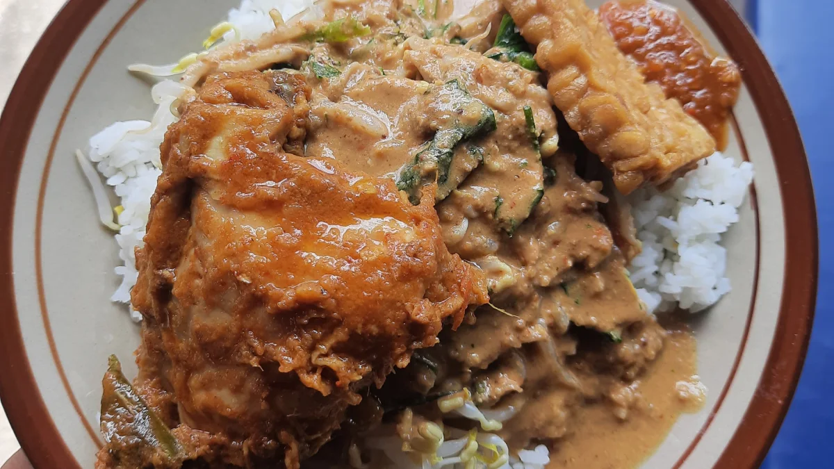 Seporsi nasi pecel dengan ayam bumbu, tempe goreng, dan siraman sambal kacang