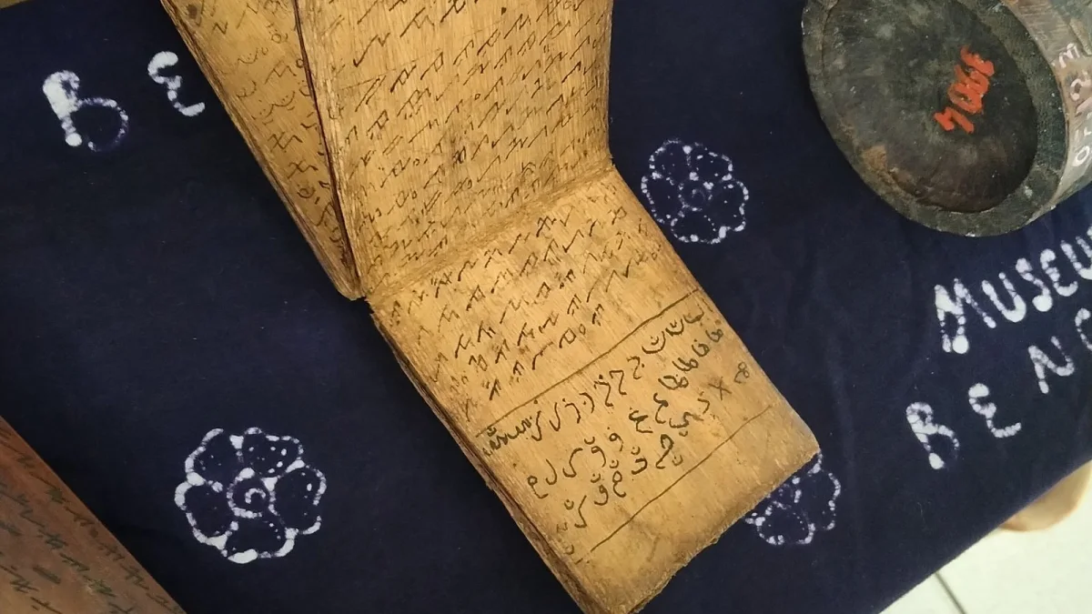 Naskah Ulu berbahan kulit kayu terbuka di atas kain biru koleksi museum