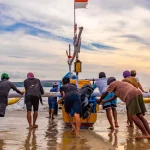 Sekelompok nelayan mendorong perahu bercadik ke laut di Pantai Kedonganan, Bali