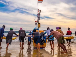Sekelompok nelayan mendorong perahu bercadik ke laut di Pantai Kedonganan, Bali