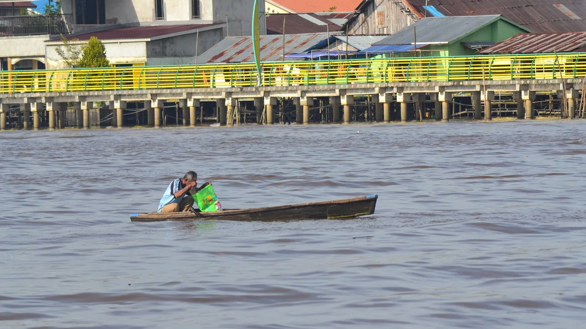 Curah Hujan Kalimantan Selatan Nyaris Nol Saat El Nino 2 Seorang nelayan di atas perahu kecil di Sungai Kapuas dengan latar rumah tepi sungai