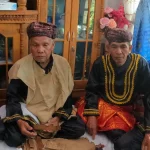 Empat pemangku adat Kerinci berbaju hitam bersulam emas dan berkuluk duduk bersila di rumah adat