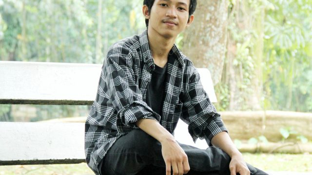 Ilustrasi seorang lelaki duduk di bangku batu di bawah rindang pepohonan Kebun Raya Bogor.