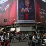 Kendaraan melintas di depan papan besar bergambar Donald Trump di sebuah kota di Iran