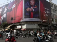 Kendaraan melintas di depan papan besar bergambar Donald Trump di sebuah kota di Iran