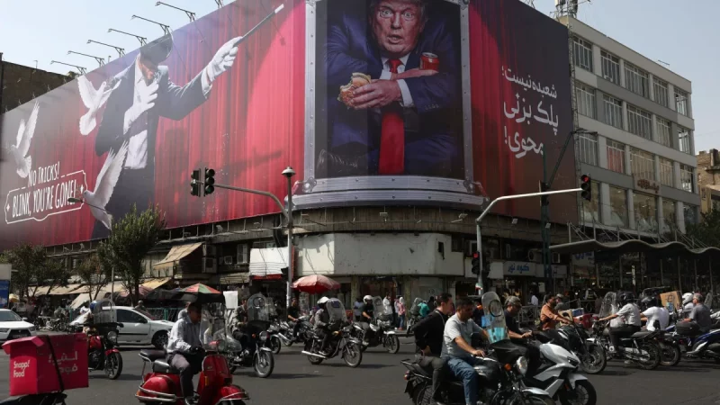 Kendaraan melintas di depan papan besar bergambar Donald Trump di sebuah kota di Iran