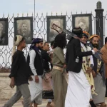 Pendukung Houthi berjalan di Sanaa, Yaman, dengan poster ilmuwan Iran yang tewas dalam serangan Israel di latar belakang.
