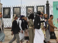 Pendukung Houthi berjalan di Sanaa, Yaman, dengan poster ilmuwan Iran yang tewas dalam serangan Israel di latar belakang.