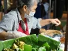Pedagang lansia menata jajanan berdaun pisang di pasar malam Chon Buri, Thailand