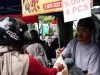 Pedagang makanan jalanan menyerahkan pesanan kepada pembeli berhelm di lapak pasar, Jawa Barat