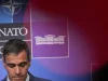 Pedro Sanchez menunduk di depan papan latar belakang berlogo NATO