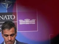 Pedro Sanchez menunduk di depan papan latar belakang berlogo NATO