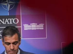 Pedro Sanchez menunduk di depan papan latar belakang berlogo NATO