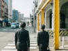 Dua pekerja kantoran pria berjas gelap bersiap menyeberang zebra cross di jalan kota Jepang