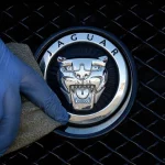 Foto arsip pekerja memoles logo Jaguar pada sebuah mobil di diler Jaguar di London